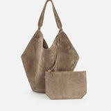 The KHAITE Lotus Medium Suede Tote Bag in taupe features two handles, a lightweight design, and a removable rectangular zippered pouch, all shown against a plain white background.