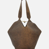 The Lotus Small Tote Bag by KHAITE is a brown, oversized, slouchy distressed leather tote crafted in Italy, featuring wide handles and a gold chain detail across the top opening. Shown against a plain white background, this bag is perfect for elevating any minimalist wardrobe.