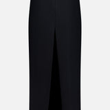 The Lyle Column Skirt by KHAITE is a black, knee-length Italian-made pencil skirt with a high front-center slit and concealed back zipper—ideal for minimalist style. Shown on a plain white background.