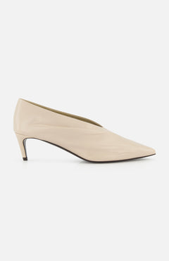 The KHAITE Miriam Glazed Leather Pump 50 is a nude pointed-toe heel with a low profile and smooth finish, perfect for minimalist looks, shown side-on against a plain white background.