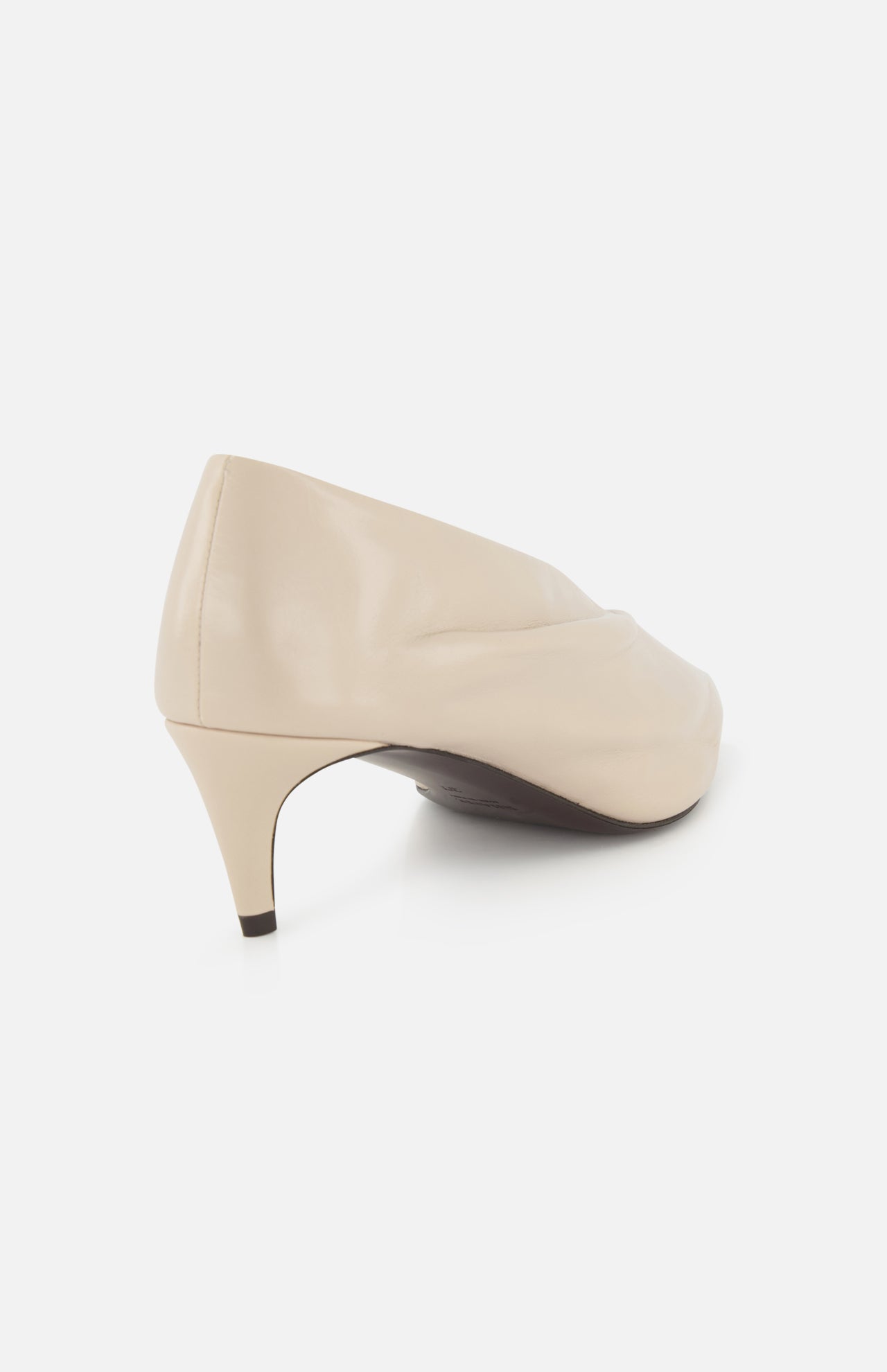 The Miriam Glazed Leather Pump 50 by KHAITE features beige nude glazed leather with a subtle wrinkled texture and a pointed toe heel, shown from the back and side on a white background—ideal for minimalist style.