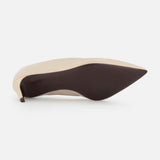 The Miriam Glazed Leather Pump 50 by KHAITE, in beige with a pointed toe and smooth dark sole, showcases an elegant silhouette—an essential piece for any minimalist wardrobe.