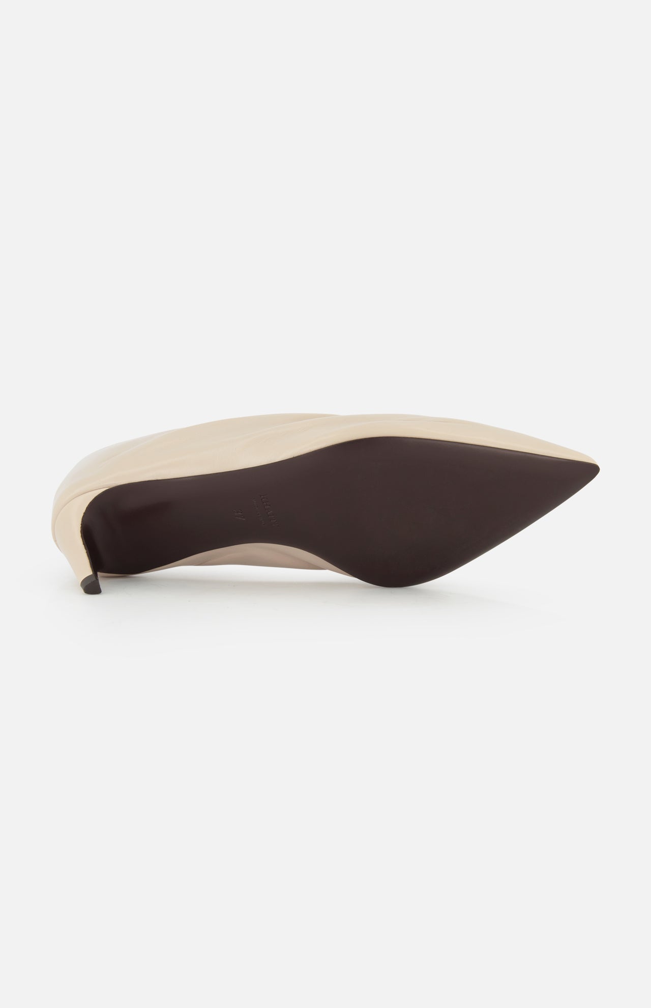 The Miriam Glazed Leather Pump 50 by KHAITE, in beige with a pointed toe and smooth dark sole, showcases an elegant silhouette—an essential piece for any minimalist wardrobe.