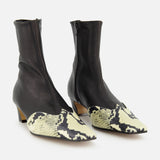 The KHAITE Nevada Ankle Stretch Boot in Python features black uppers, pointed toes, python wingtip accents, low heels, side zippers, and a sleek modern design for a refined update to the classic cowboy boot.