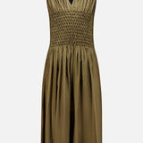 The KHAITE Nola Smocked Waist Dress is a sleeveless dark olive design featuring a deep V-neckline, hand-smocked waist, pleated bodice, and softly gathered knee-length skirt, shown against a white background.