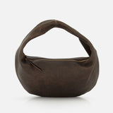 The KHAITE Olivia Hobo Medium Shoulder Bag is a brown, crescent-shaped shoulder bag crafted from distressed leather, featuring a curved handle and an exposed gold zipper. It is shown against a plain white background.