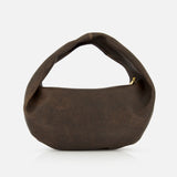 The Olivia Hobo Medium Shoulder Bag by KHAITE is a brown, crescent-shaped medium hobo crafted from distressed leather with a wide, curved handle, shown against a plain white background.