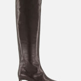 Introducing the Ona Knee High Boot by KHAITE: a tall, dark brown leather boot handcrafted in Italy, showcasing a knee-high silhouette with a pointed toe and a low, slender heel, photographed against a white background.