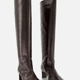 The Ona Knee High Boot by KHAITE is a pair of tall, dark brown leather boots featuring square toes and low block heels, expertly crafted in Italy and standing upright on a plain light background.