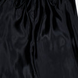 The KHAITE Rohen Satin Bow-leg Pant features a glossy black finish, elastic waistband, and drawstring tie. Its smooth texture and relaxed silhouette make it a versatile staple for any minimalist wardrobe. Displayed flat.