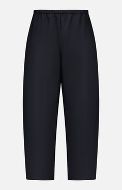 The KHAITE Roma Cropped Pull-on Pant is a pair of plain black, loose-fitting pants made from lightweight wool suiting with an elastic waistband and no visible pockets, shown on a white background.