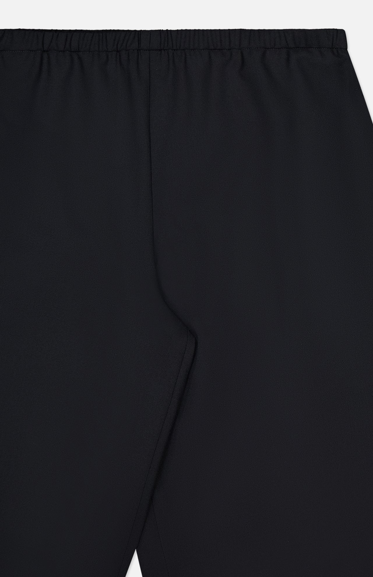 Close-up of the KHAITE Roma Cropped Pull-on Pant in black, featuring an elastic waistband and smooth, pattern-free lightweight wool suiting for comfort and style.