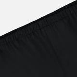 Close-up of the waistband on KHAITE's Roma Cropped Pull-on Pant in black, showing an elastic band and seam details. Made from lightweight wool suiting with a smooth, slightly shiny finish. Light gray background.