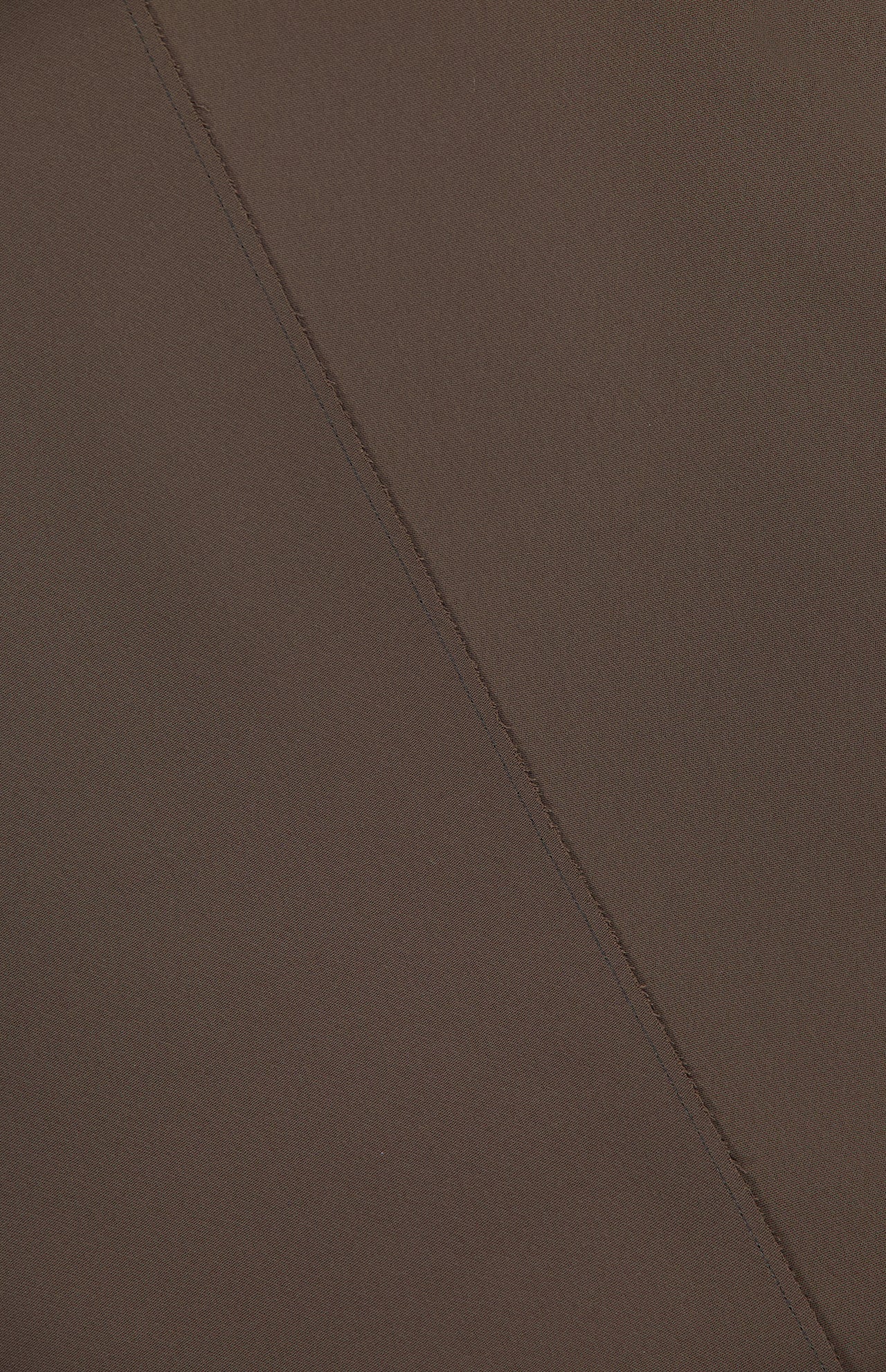 A close-up of the Rone Open Back Halter Top by KHAITE, showing brown double-faced crepe fabric with a visible diagonal seam from top left to bottom right. The material looks smooth and evenly colored.