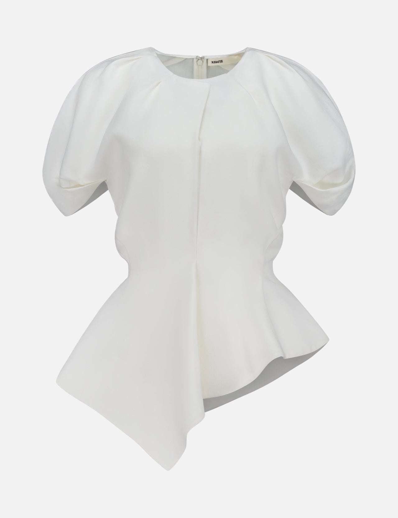 The Rumi Asymmetric Hem Top by KHAITE is a white short-sleeve blouse featuring puffed shoulders, a fitted waist, and an asymmetric hem. Crafted from a luxurious linen-viscose-silk blend, this draped top is displayed on a plain white background.