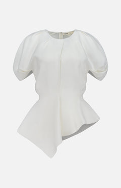 The Rumi Asymmetric Hem Top by KHAITE is a white short-sleeve blouse featuring puffed shoulders, a fitted waist, and an asymmetric hem. Crafted from a luxurious linen-viscose-silk blend, this draped top is displayed on a plain white background.
