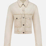 The Tomer Collared Cropped Denim Jacket by KHAITE features beige denim, a pointed collar, button-down front, long sleeves, and two chest flap pockets—perfect for a minimalist wardrobe. Shown on a white background.