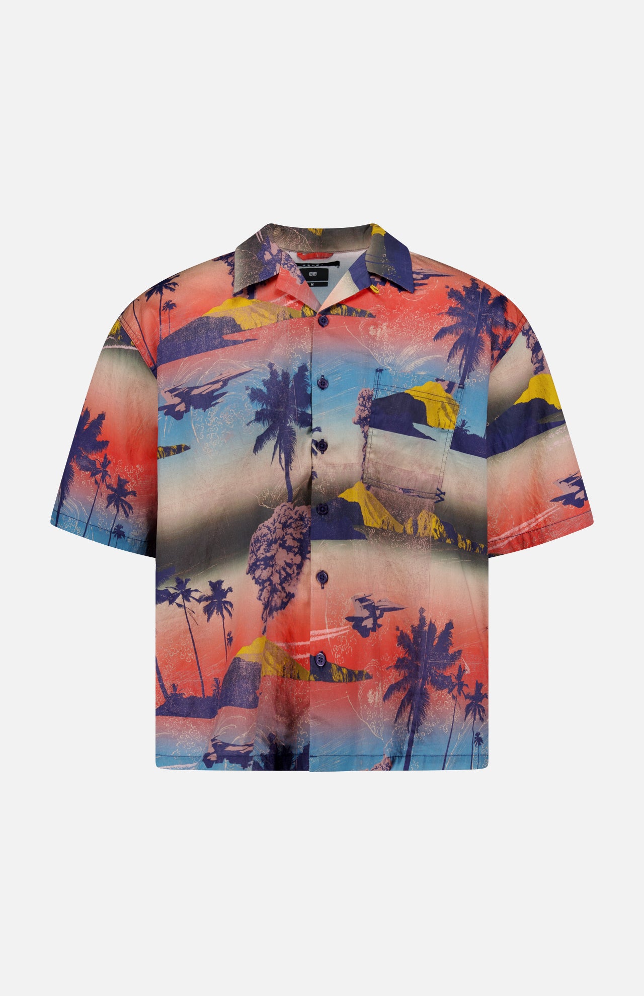 The KSUBI Mauna Loa Short Sleeve Diner Shirt is an oversized cotton modal shirt with a vivid tropical print of palm trees, mountains, and oceans in bold red, blue, yellow, and purple hues.