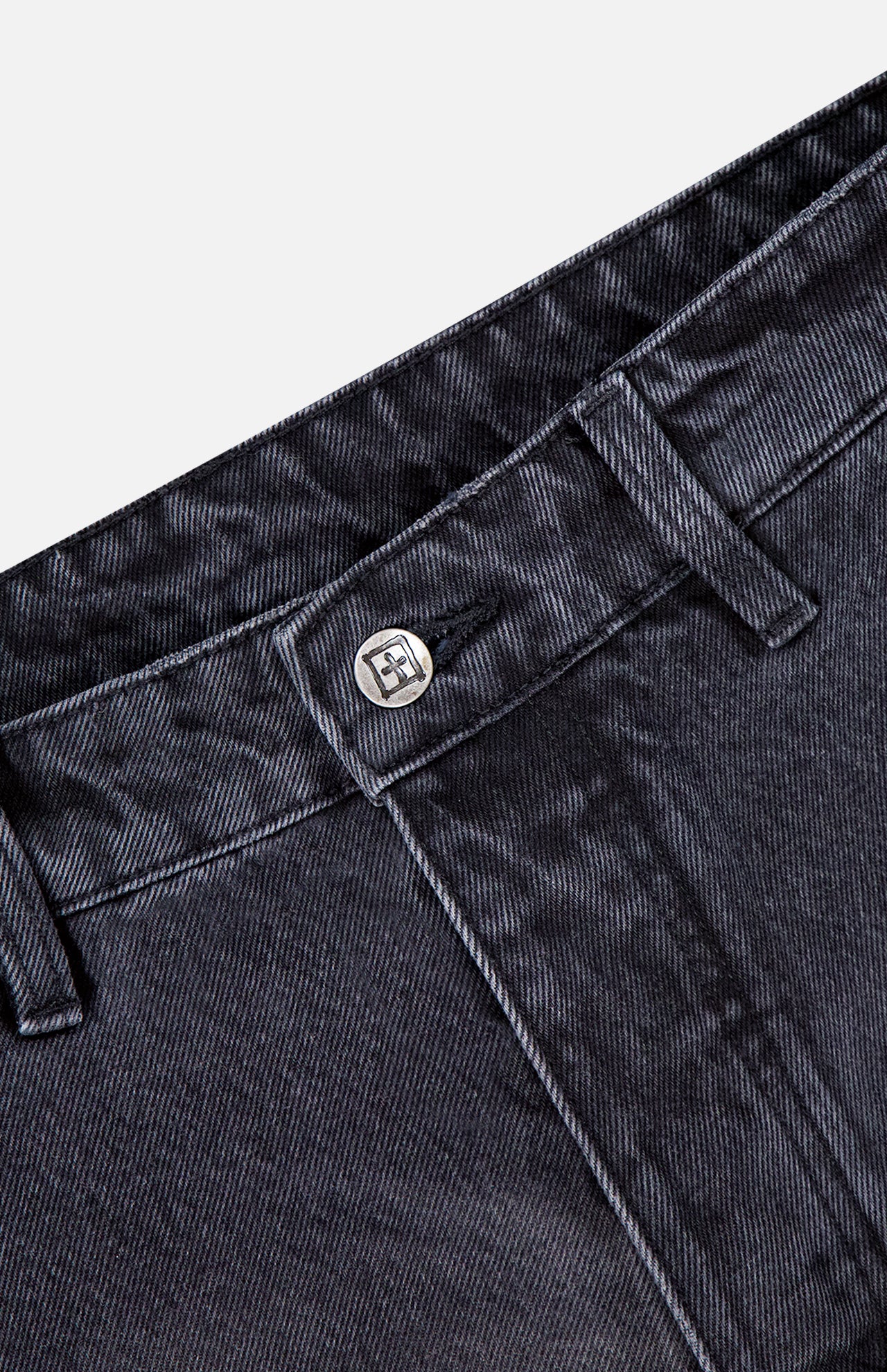 Close-up view of the waistband and button on KSUBI Maxx Operator Jean Shorts, highlighting belt loops, stitched detailing, textured dark black denim, and a glimpse of a carpenter pocket.