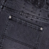 Close-up of the back carpenter pocket on KSUBI Maxx Operator Jean Shorts in black denim, featuring subtle water spots above the pocket and two metal rivets at the corners.