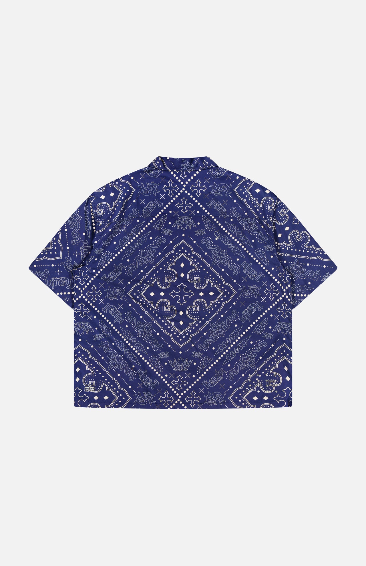 A navy short-sleeve Paise Diner Shirt by KSUBI, featuring a white paisley bandana print and a classic Cuban collar, displayed flat with the back side facing up.