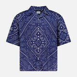 The KSUBI Paise Diner Short Sleeve Shirt is a navy blue, short-sleeved button-up featuring a Cuban collar and an intricate white paisley bandana print in a symmetrical design.