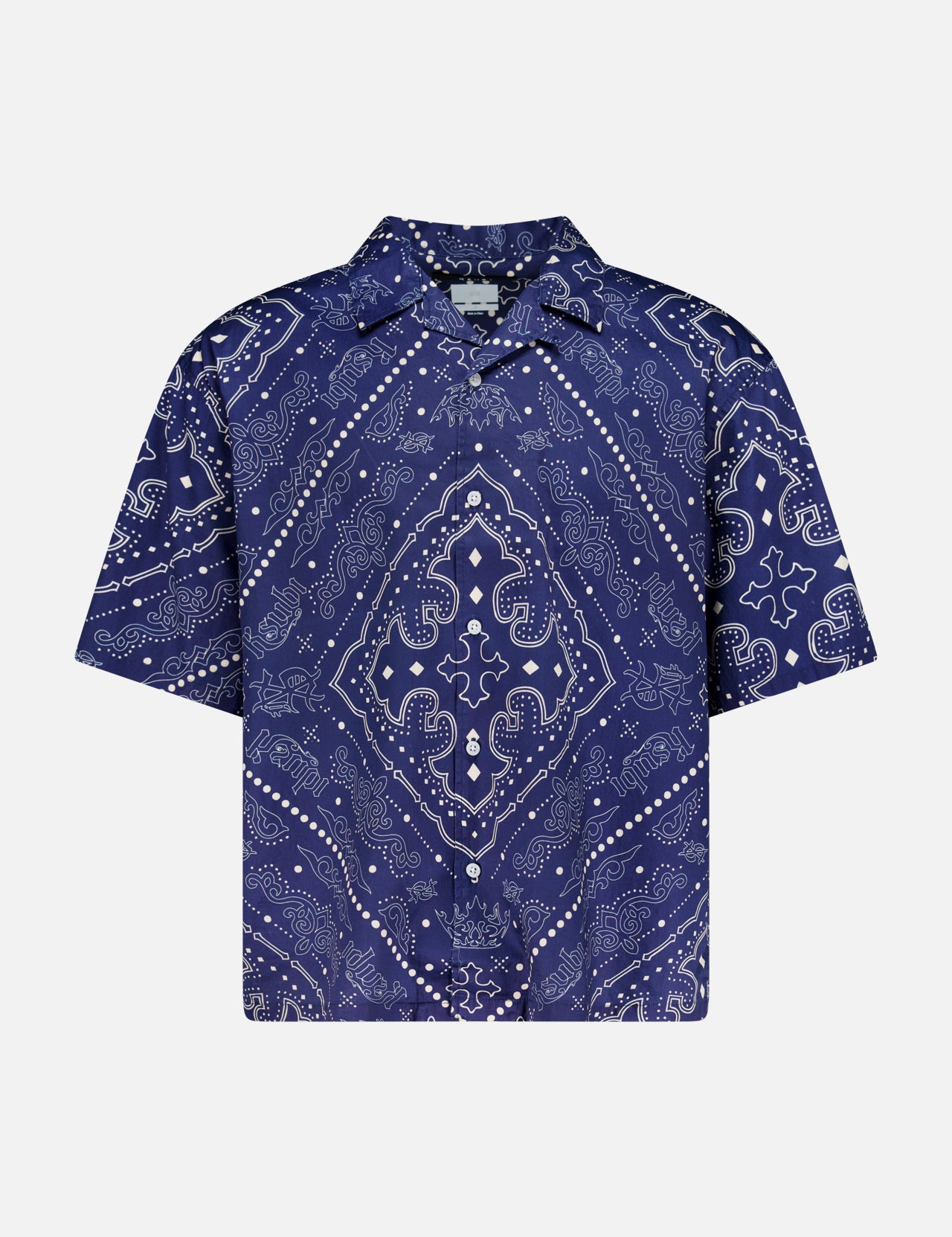 The KSUBI Paise Diner Short Sleeve Shirt is a navy blue, short-sleeved button-up featuring a Cuban collar and an intricate white paisley bandana print in a symmetrical design.