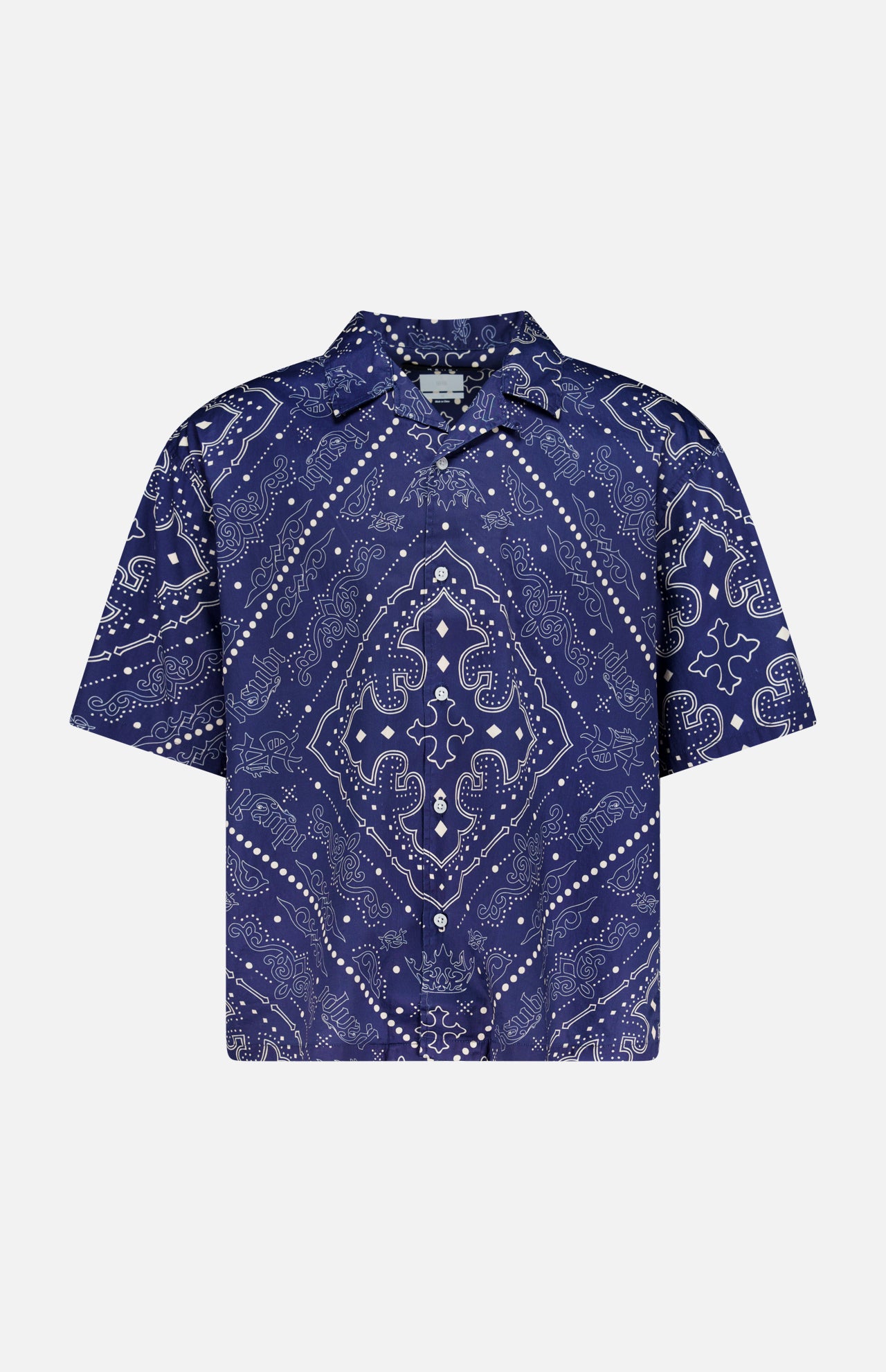 The KSUBI Paise Diner Short Sleeve Shirt is a navy blue, short-sleeved button-up featuring a Cuban collar and an intricate white paisley bandana print in a symmetrical design.