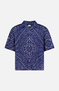 The KSUBI Paise Diner Short Sleeve Shirt is a navy blue, short-sleeved button-up featuring a Cuban collar and an intricate white paisley bandana print in a symmetrical design.