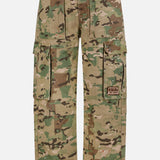 The KSUBI Trooper Camouflage Cargo Pant features a green and brown woodland camo, relaxed leg, multiple pockets including large zippered sides, metal D-rings, and a KSUBI logo patch on the right pocket.