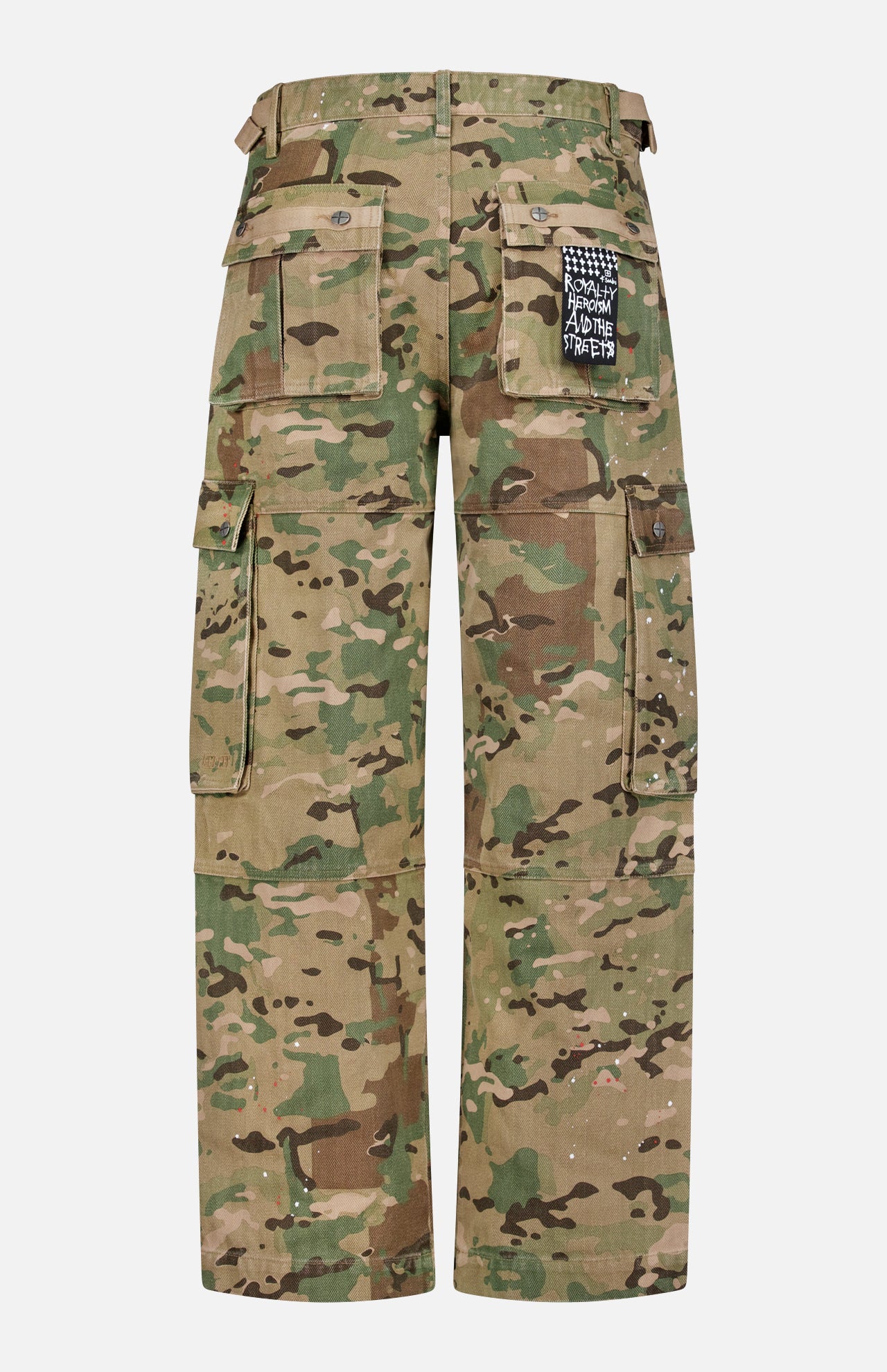 The KSUBI Trooper Camouflage Cargo Pant is shown from the back in green, brown, and beige tones, featuring multiple large pockets and a black-and-white text patch on the right back pocket with a relaxed leg fit.