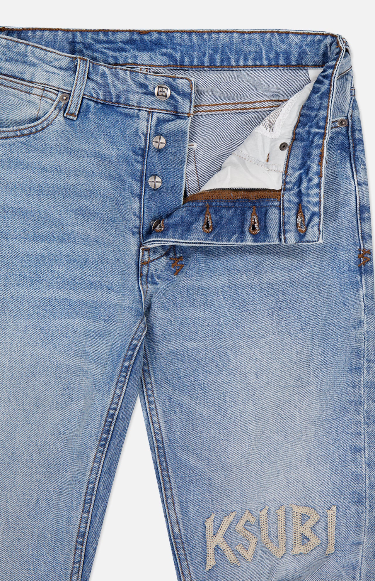 The KSUBI Van Winkle Duke 4Eva Jeans are crafted from comfort stretch denim for an easy fit, featuring light blue faded and distressed detailing throughout. These skinny jeans have a partially open button fly that reveals white pocket lining, while large white KSUBI embroidery stands out near the left front pocket.