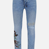 The Van Winkle Duke 4Eva Jeans by KSUBI are light blue skinny jeans made from comfort stretch denim, adorned with bold tiger embroidery and a leaf detail on one thigh, and feature the brand’s signature “KSUBI” embroidered above a rip on the other thigh.