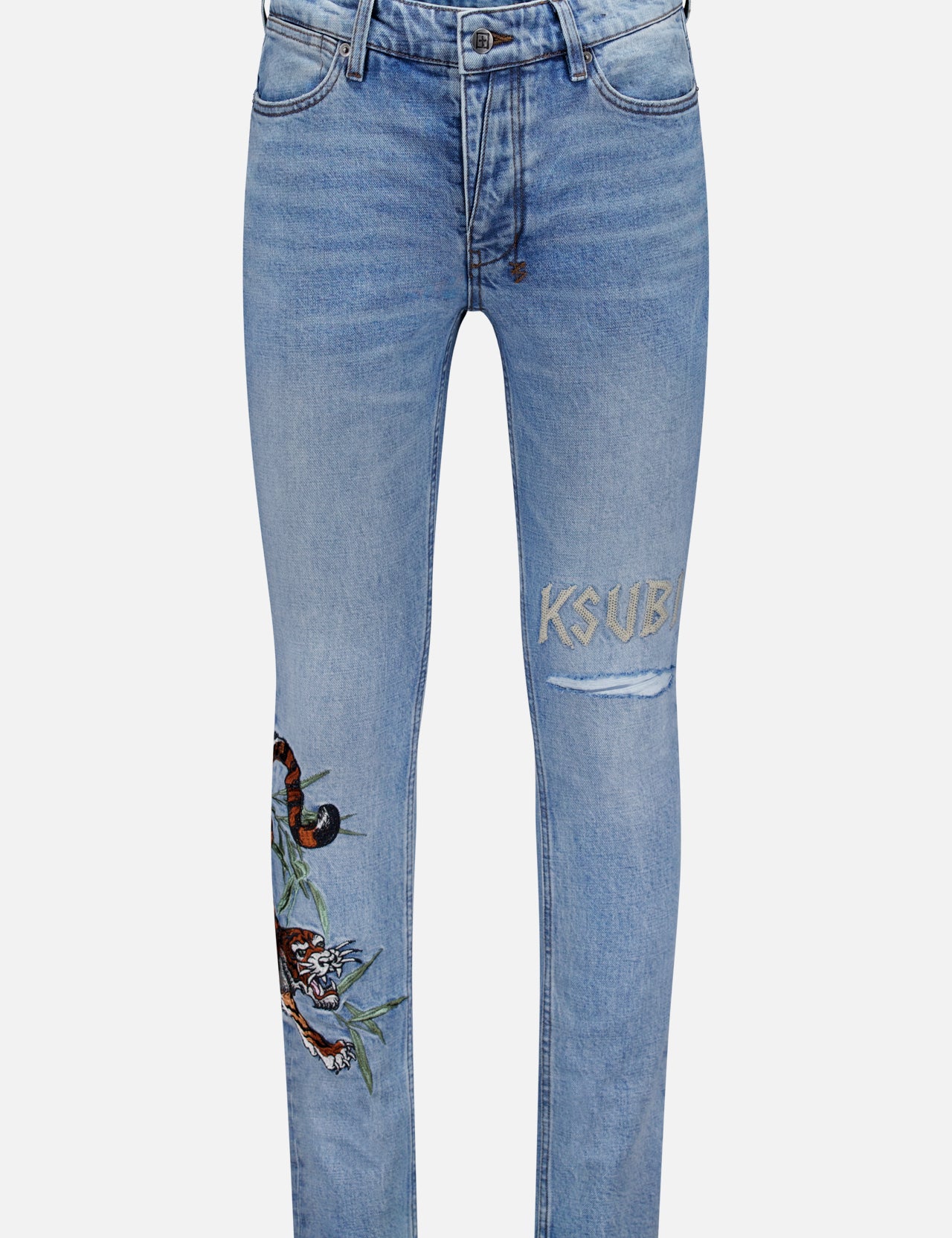 The Van Winkle Duke 4Eva Jeans by KSUBI are light blue skinny jeans made from comfort stretch denim, adorned with bold tiger embroidery and a leaf detail on one thigh, and feature the brand’s signature “KSUBI” embroidered above a rip on the other thigh.