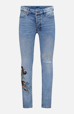 The Van Winkle Duke 4Eva Jeans by KSUBI are light blue skinny jeans made from comfort stretch denim, adorned with bold tiger embroidery and a leaf detail on one thigh, and feature the brand’s signature “KSUBI” embroidered above a rip on the other thigh.