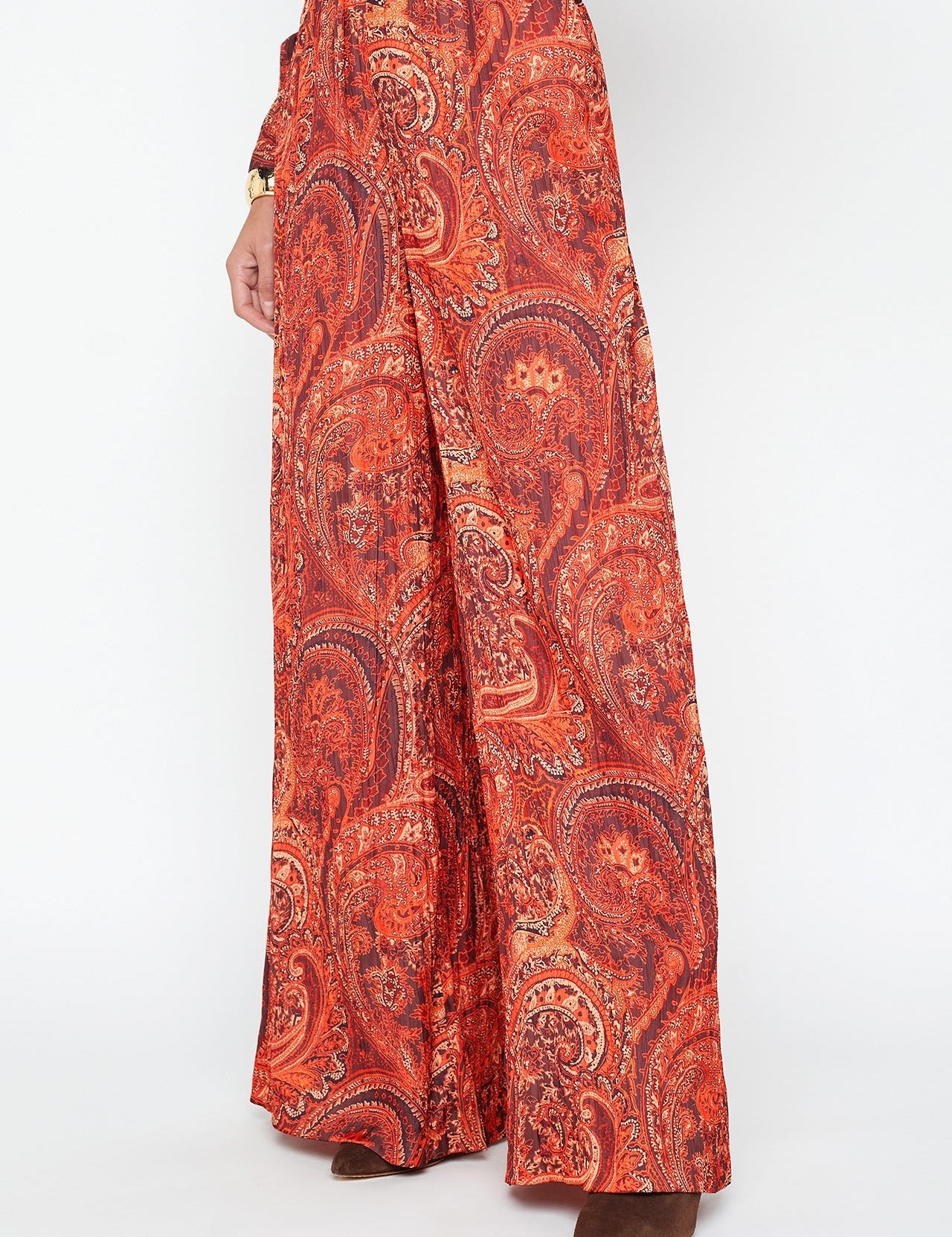 A person wears the Lillian Wide Leg Pant by L'AGENCE in vibrant burnt orange paisley crinkled satin, styled with brown pointed-toe shoes. The photo is cropped above the waist.