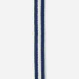 A close-up of the LA BOUCLE Bristol Chevron Club Belt shows its navy and white zigzag pattern with a central white stripe, dark leather tip, and stretch fit—making this stylish belt a comfortable, one-size-fits-all golf accessory.