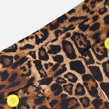 Close-up of the Cyra Low Rise Mini Skirt by L'AGENCE, showcasing leopard print fabric with black and brown spots and two yellow buttons, set against a white background.