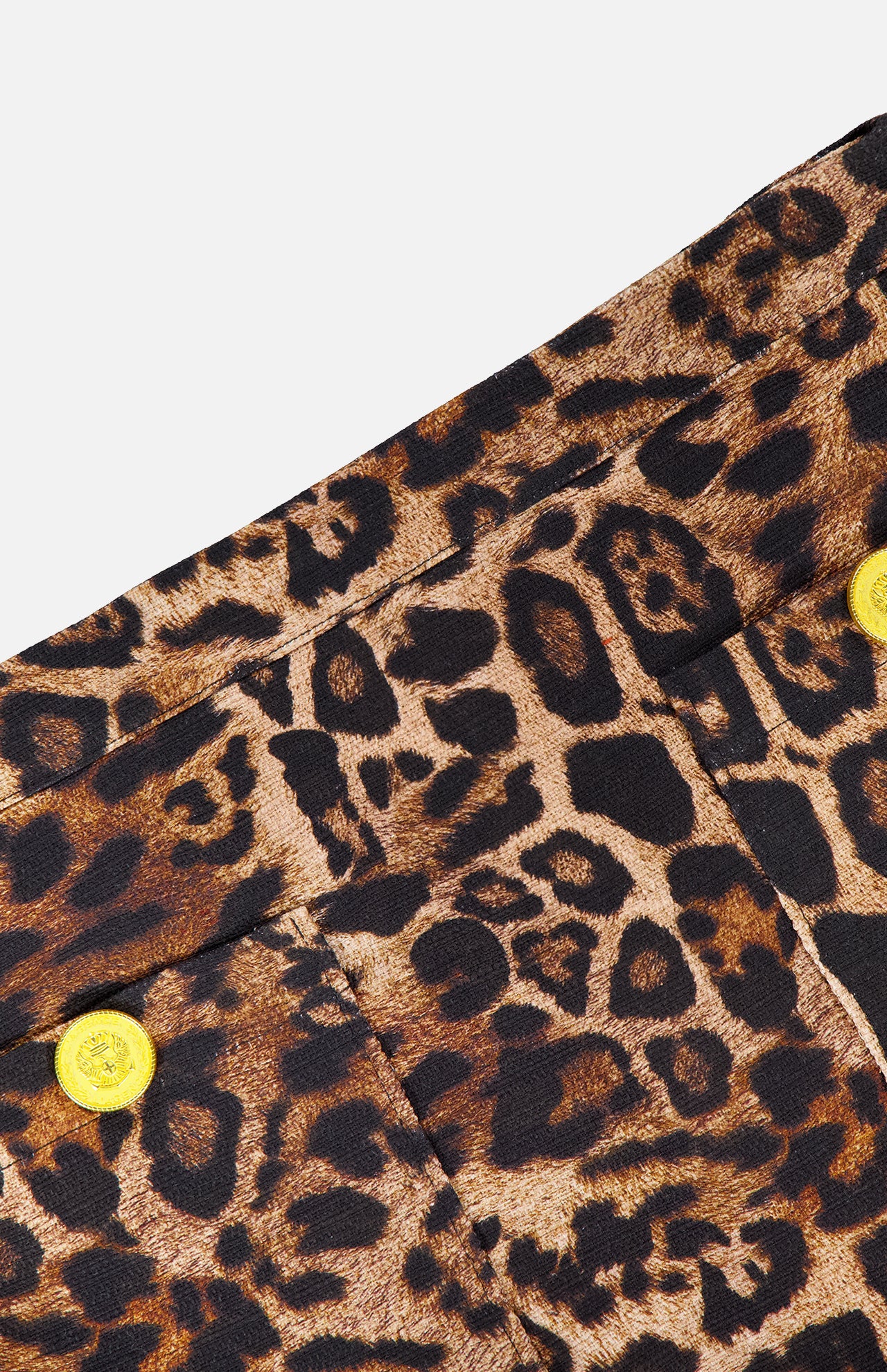Close-up of the Cyra Low Rise Mini Skirt by L'AGENCE, showcasing leopard print fabric with black and brown spots and two yellow buttons, set against a white background.