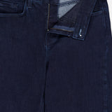 Close-up of Marguerite High Rise Skinny Jean in dark blue stretch denim with pocket, zipper fly, and button. The waistband is partially open, revealing a brand label reading L'Agence inside.