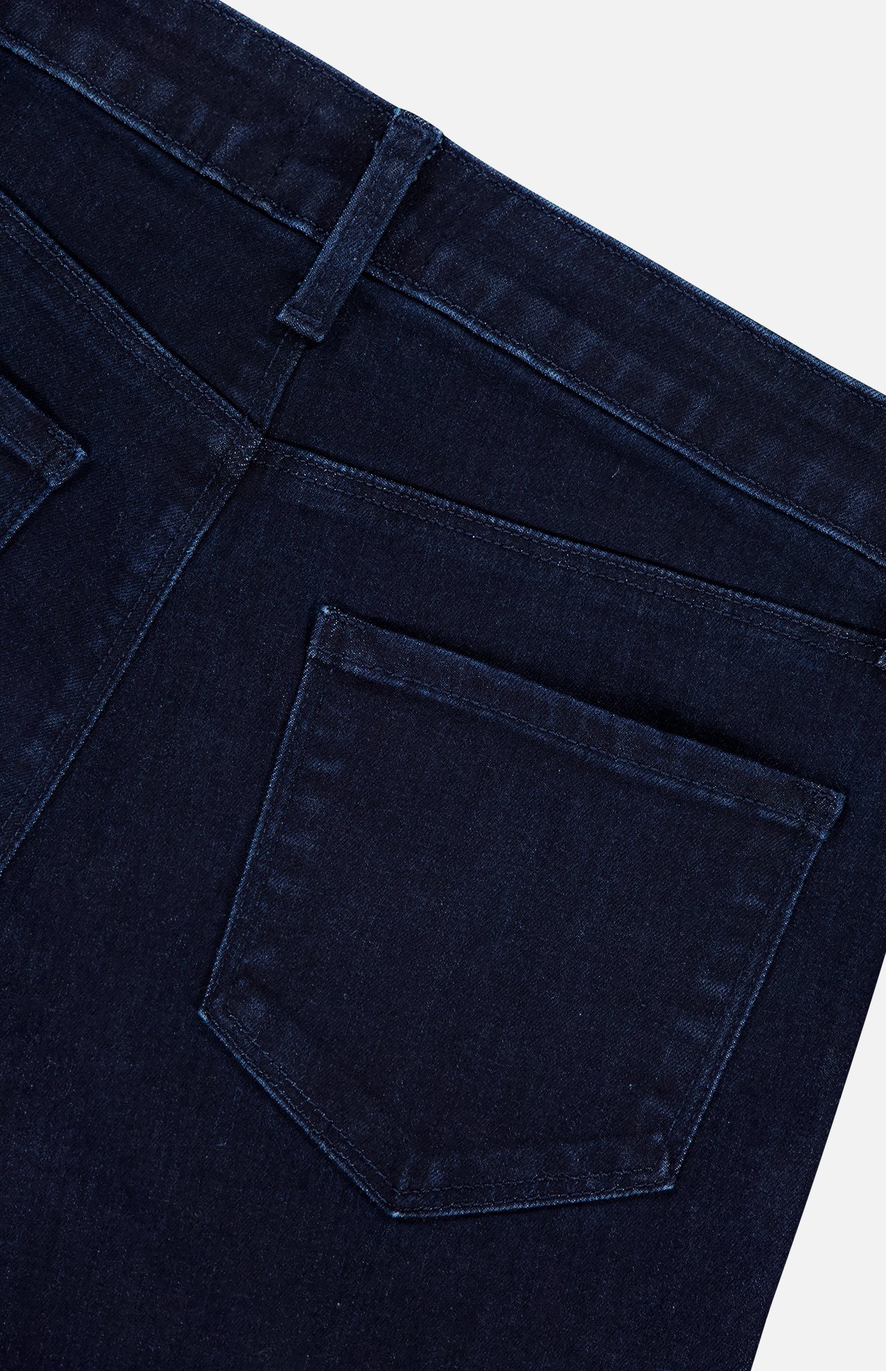 Close-up of the back of L’Agence Marguerite High Rise Skinny Jean in dark blue stretch denim, highlighting waistband, belt loop, two seams, and a single back pocket against a light background.