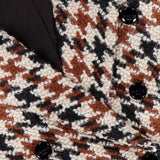 Close-up of L'AGENCE Marie Double Breasted Houndstooth Blazer in brown, black, and white boucle with black buttons and a visible label—ideal for a cinched-waist tweed look.