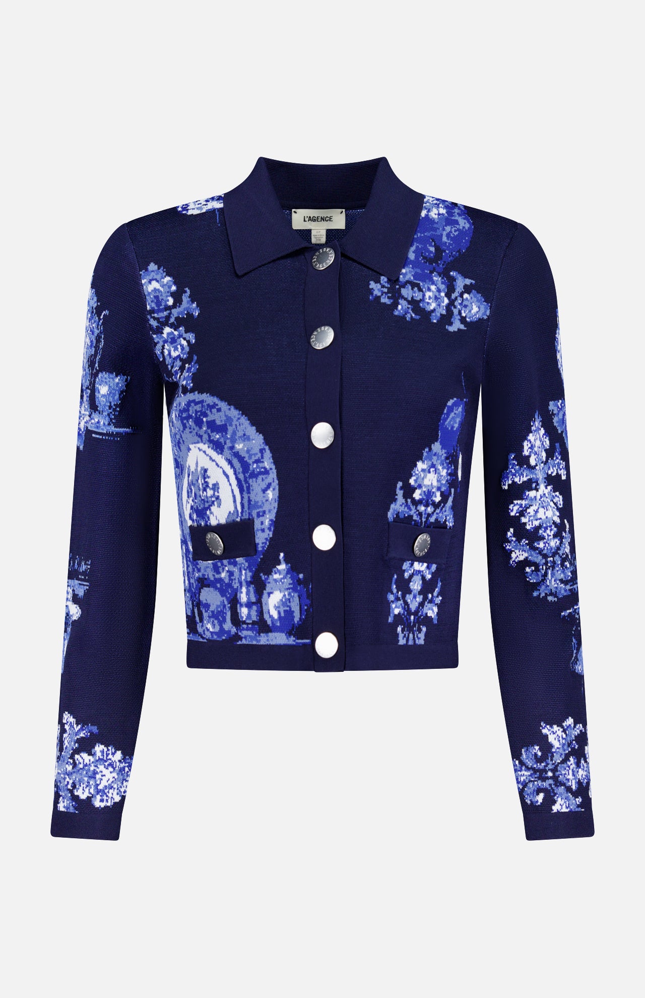 The Osiris Jacquard Collared Cardigan by L'AGENCE is a navy blue, long-sleeve cropped statement piece with silver buttons and a pixelated blue and white porcelain motif of plates, vases, and florals.