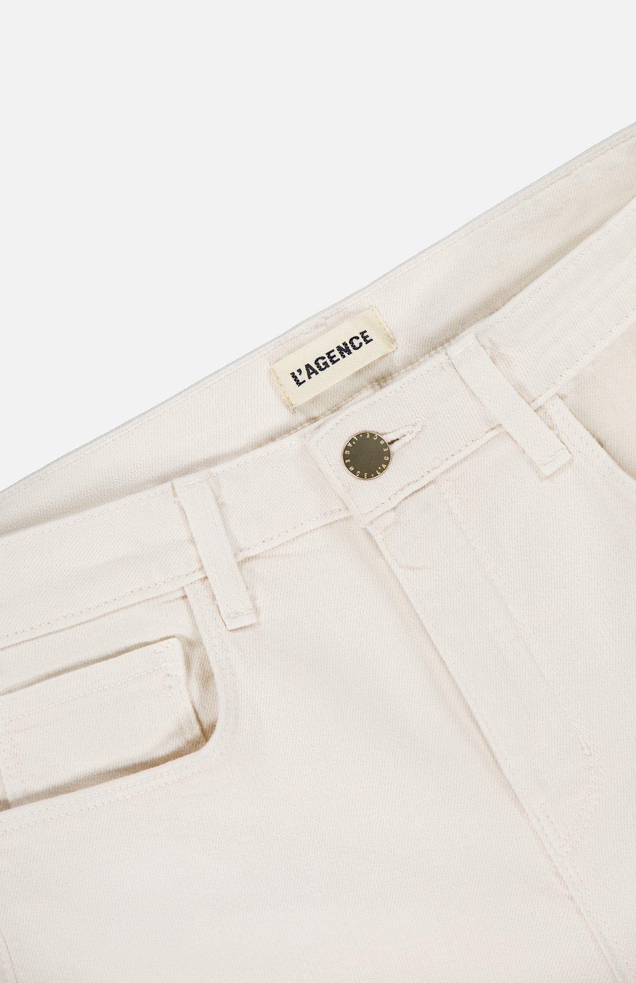 Close-up of the waistband on the cream Ruth High Rise Straight Jean by L’AGENCE, featuring premium stretch denim, a metal button, belt loops, coin pocket, and an interior L’AGENCE label.
