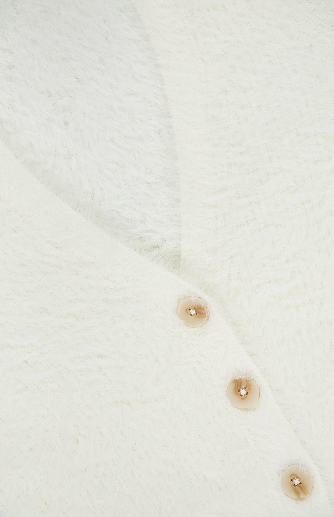 Close-up of the Agathe Fuzzy Collared Cardigan by L’AGENCE, featuring soft fuzzy white fabric and three light brown buttons.