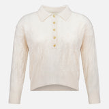 The Airy 3/4 Sleeve Heart Button Sweater by L’AGENCE features a cream cable knit design with a collared neckline and a partial button-down front adorned with five heart-shaped buttons. This vintage-inspired, long-sleeve sweater boasts a slightly cropped, uneven hem for a blend of timeless appeal and modern style.