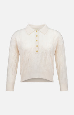 The Airy 3/4 Sleeve Heart Button Sweater by L’AGENCE features a cream cable knit design with a collared neckline and a partial button-down front adorned with five heart-shaped buttons. This vintage-inspired, long-sleeve sweater boasts a slightly cropped, uneven hem for a blend of timeless appeal and modern style.