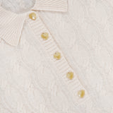 A close-up of the Airy 3/4 Sleeve Heart Button Sweater in a cream ivory hue showcases its ribbed collar and delicate, pale heart-shaped buttons along the placket. The L’AGENCE label is visible inside the collar, adding a timeless element to this elegant sweater.