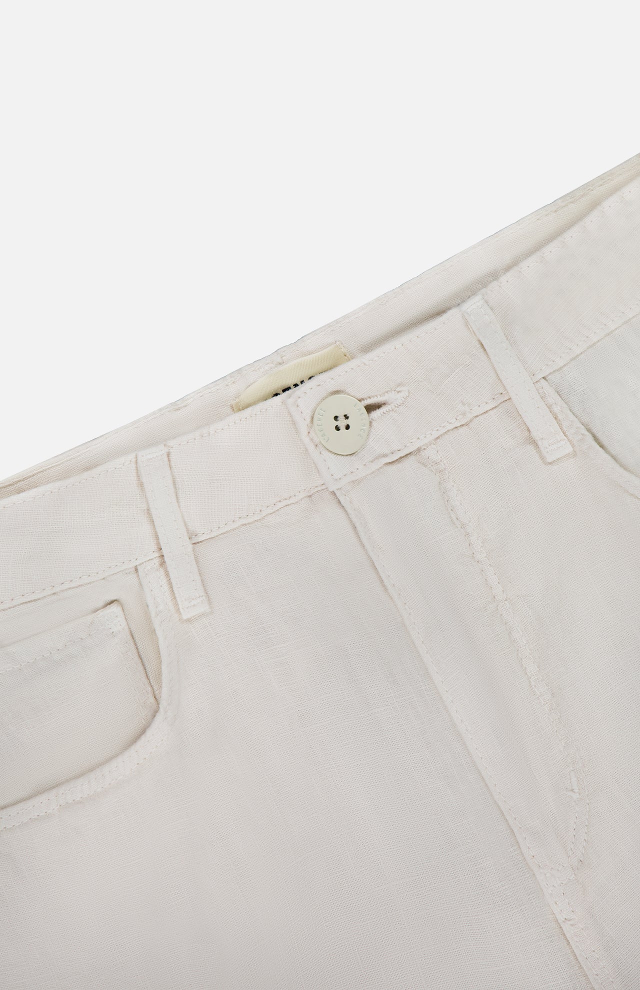 Close-up of the waistband and front pocket on the L'Agence Amara High Rise Wide Leg Pant in light beige linen, featuring a button closure, belt loops, and visible stitching.