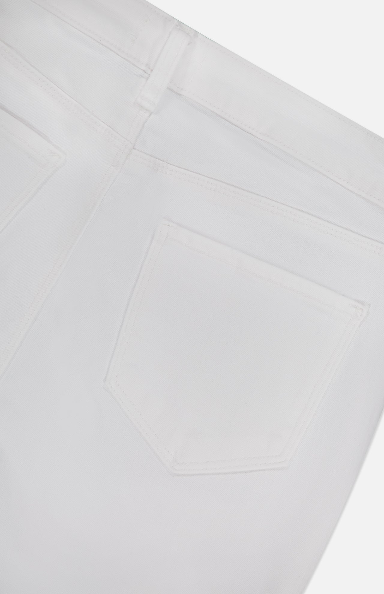 Close-up of the back of L'AGENCE Amaris High Rise Skinny Pedal Pusher Pants in white, showing the waistband, belt loop, and two back pockets. Smooth stretch ponte fabric and visible stitching enhance the sleek look.